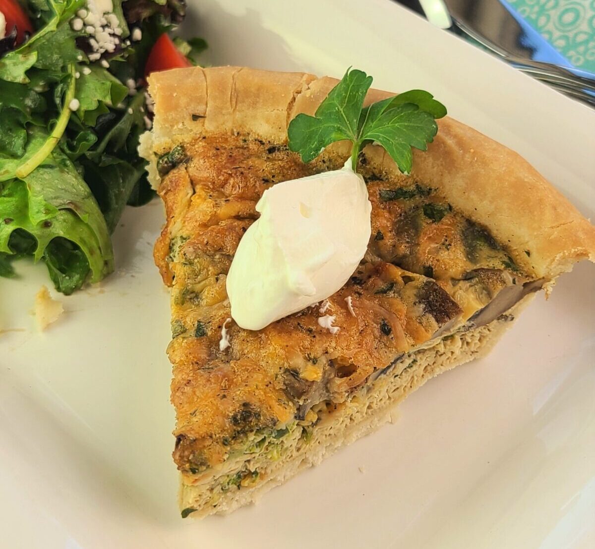 an egg quiche with a salad on a plate for breakfast